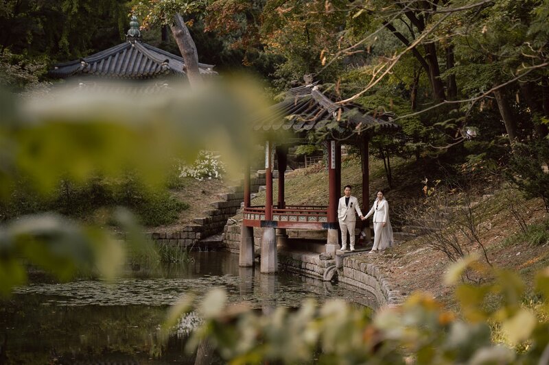bride wearing a white dress and gold hairband and groom wearing a blue tuxedo smile during after eloping in Seoul,