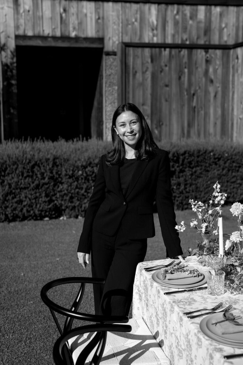 Claire Glynn poses gracefully in a black-and-white portrait beside a beautifully set table. Photo by Logan Alexander