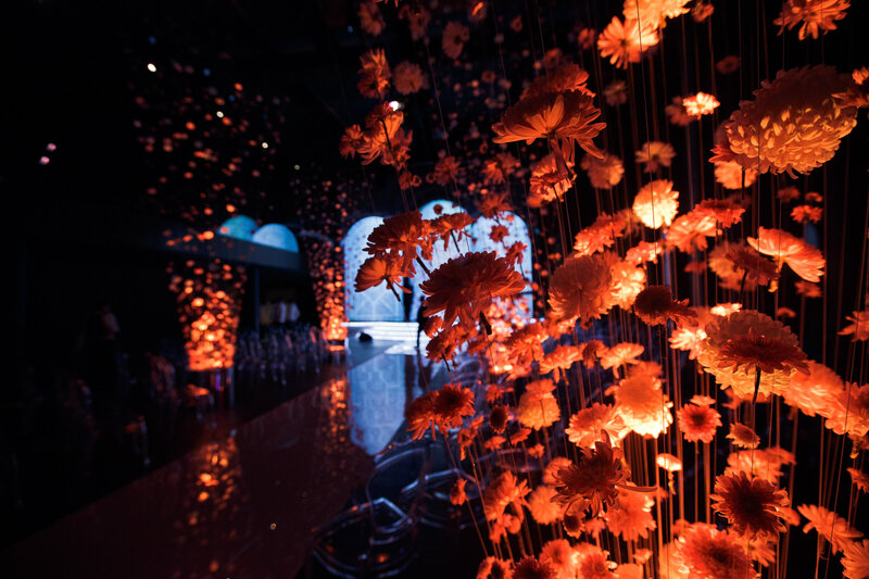 Scénographie composée de chrysanthèmes rouges suspendus pour une inauguration. Organisation d'événement d'entreprise.