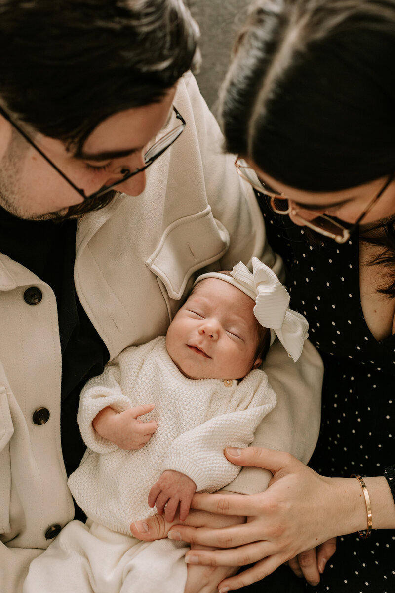 Baby girl smiling while being held by parents 