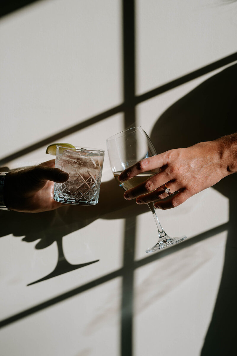 Bride and groom cheers glasses in window light