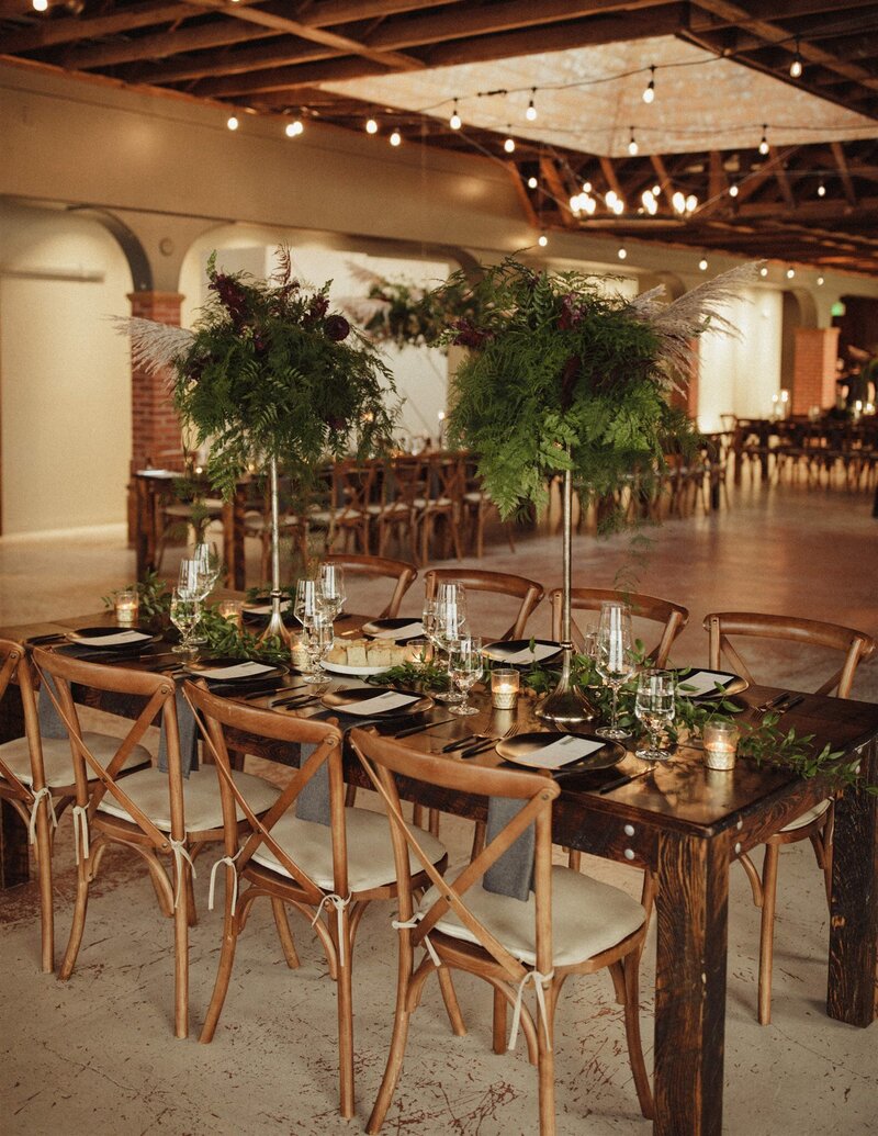 wedding reception table with 6 chairs candles and greenery