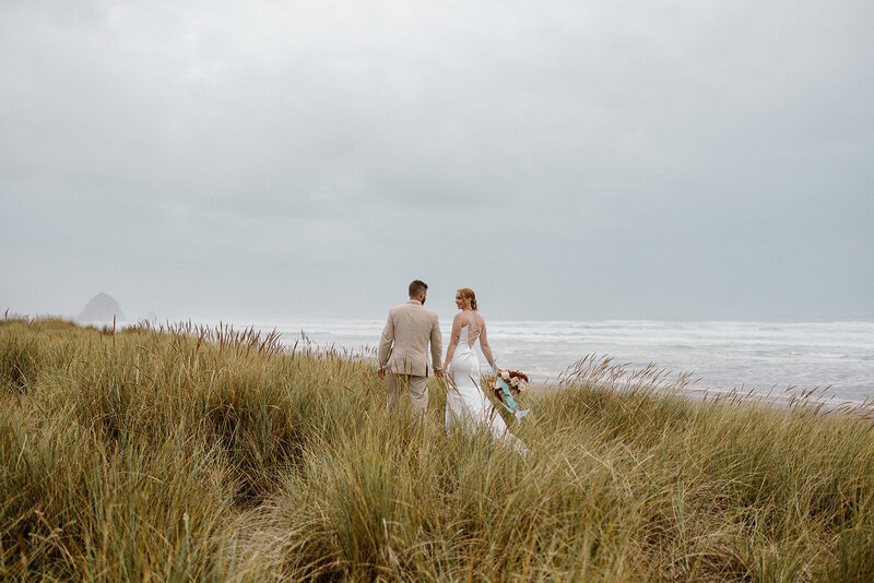 Couple walks hand in hand down the sand dunes.