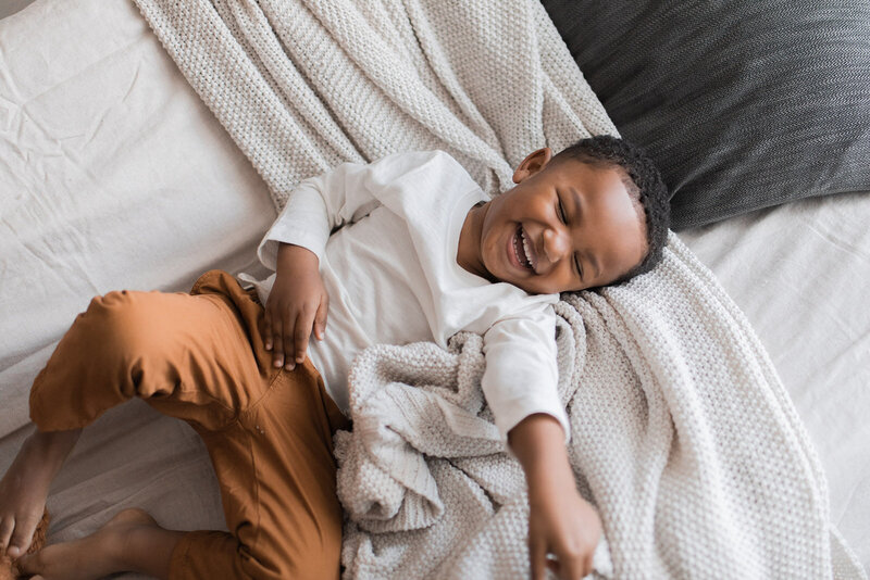 Toddler boy laughing in bed
