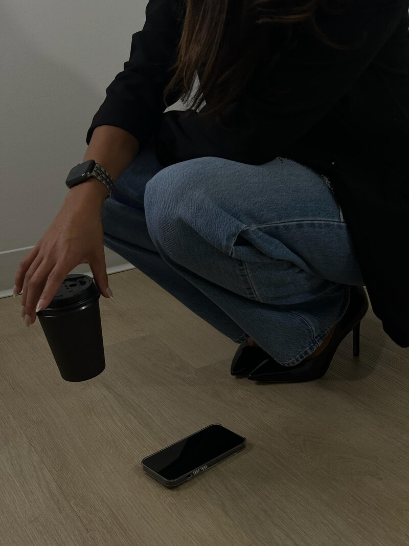 Professionally dressed woman squatting, holding a coffee