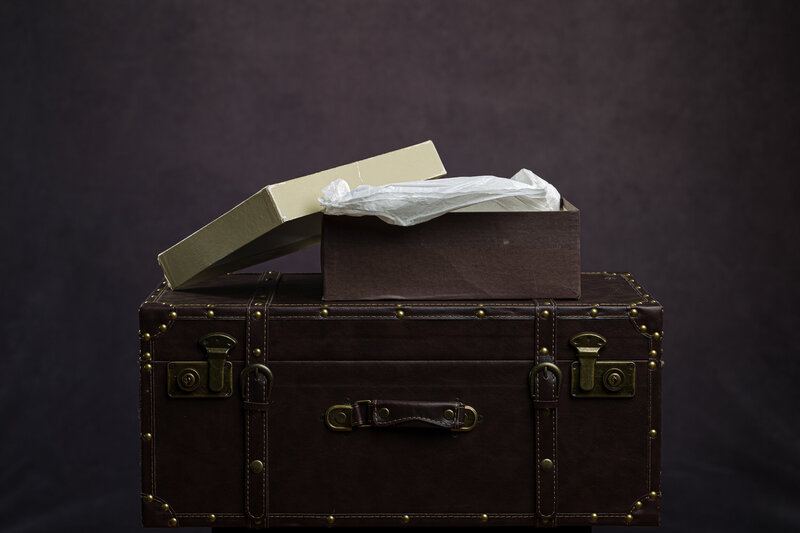 An old cardboard box with tissue paper, holding a vintage wedding album ready for restoration.