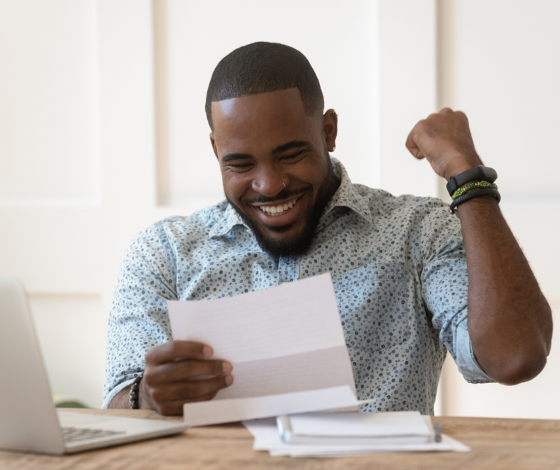 Man fist-pumping the air while reading a paper.