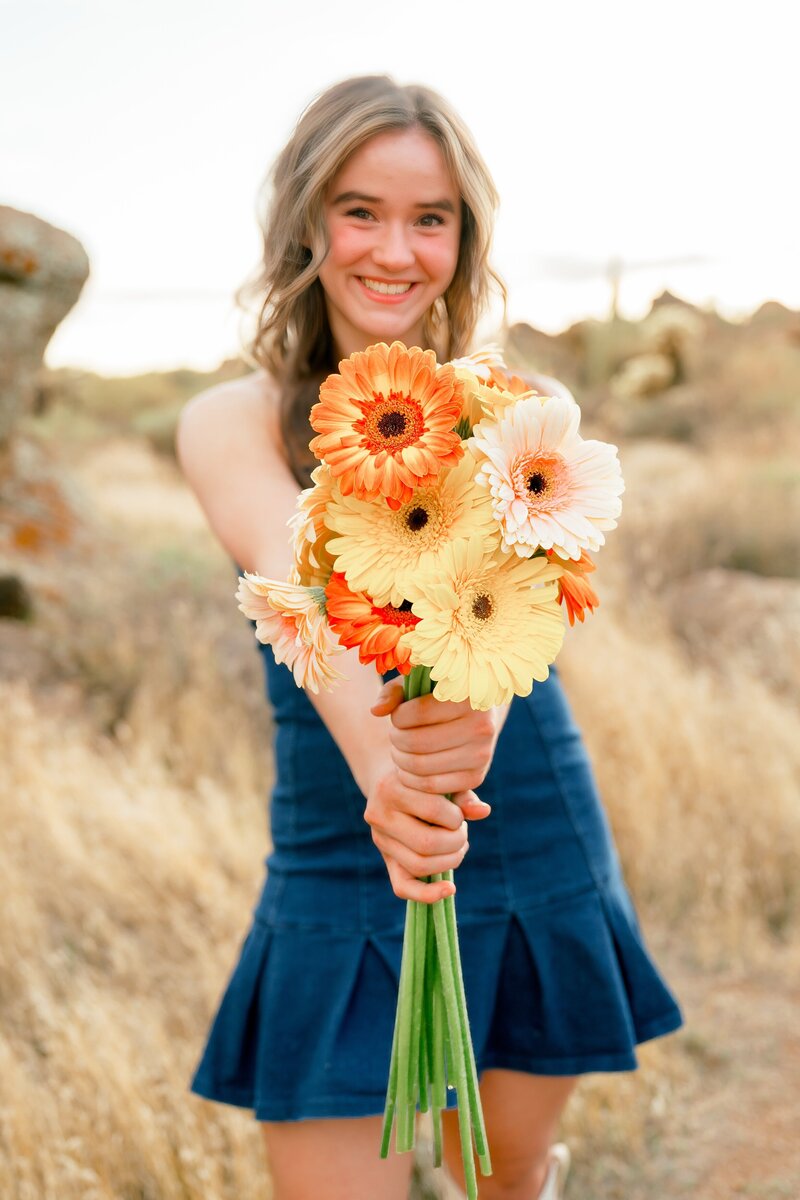 high school senior posing for senior photos with flowers in the arizona desert 