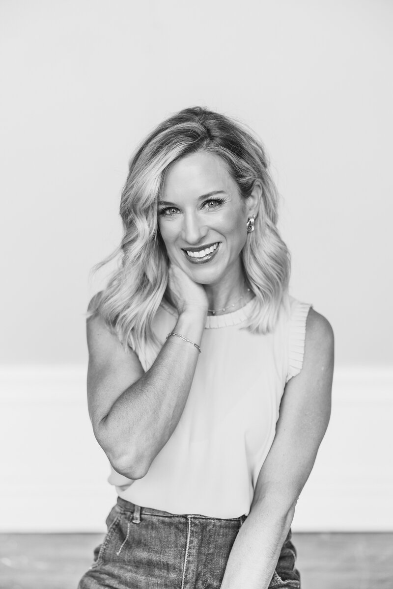 woman with dirty blonde hair, wearing white top smiling at the camera