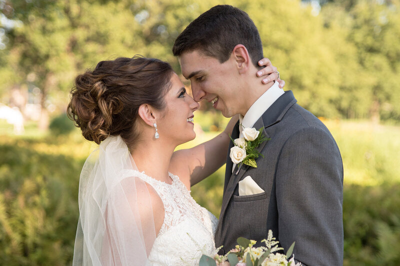 Bride and groom smile forehead to forehead on their wedding day