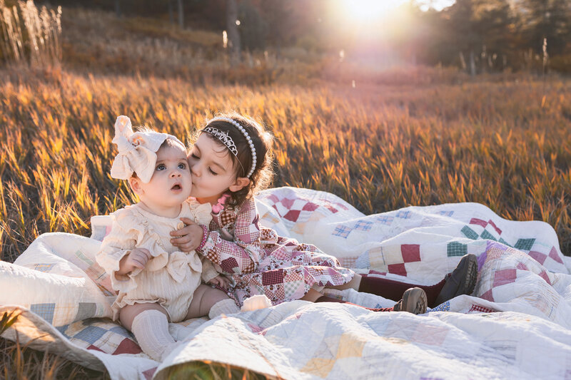 Big sisters hugging mom's pregnant belly.