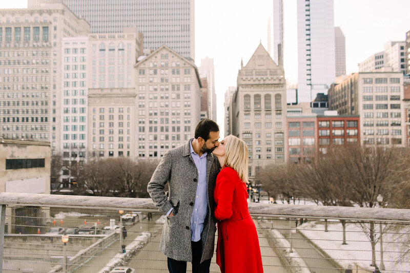 A couple kiss for an engagement photo with downtown Chicago in the backdrop