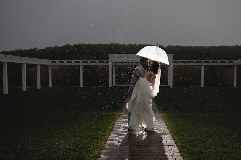 A sample image from Philadelphia wedding photographer Daring Romantics.  A couple kisses under an umbrella in the rain.