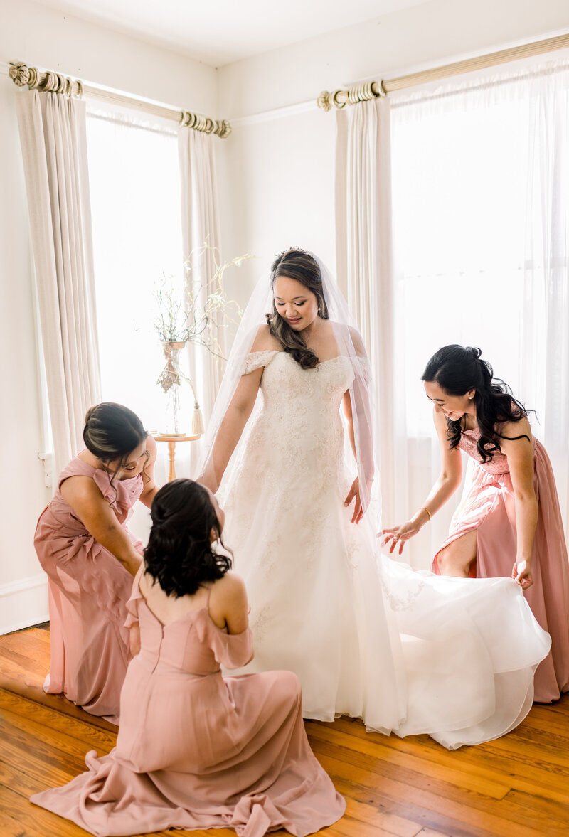 bride with bridesmaids fluffing the dress