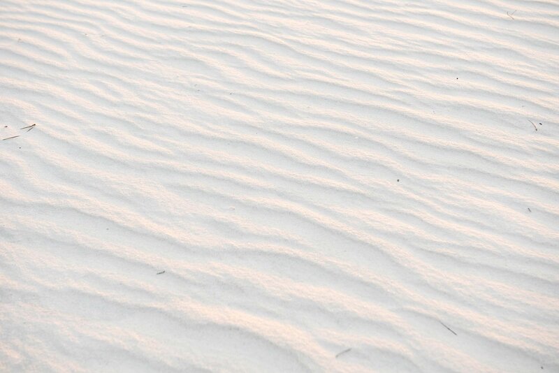Pure white sand with a rippled surface in the morning light.