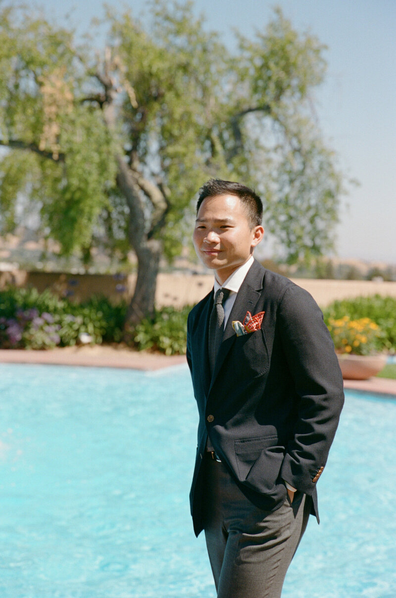 Groom standing near pool in suit, Marin Civic Center elopement.