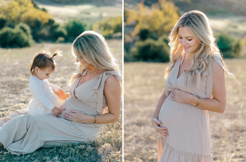 An expectant mother sits in a field with her toddler daughter on her lap looking at her baby  bump