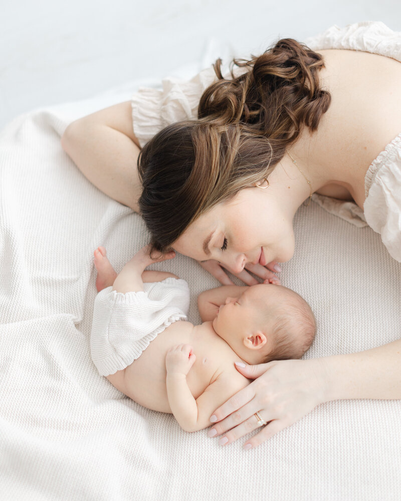 Mother snuggles with her newborn baby at newborn portrait session