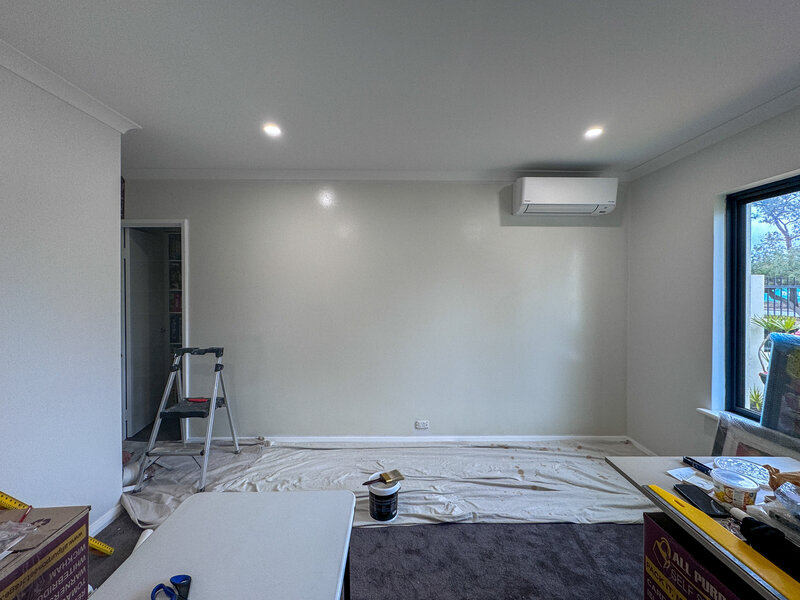 A wall prepared for wallpaper with protective sheets and a ladder around.