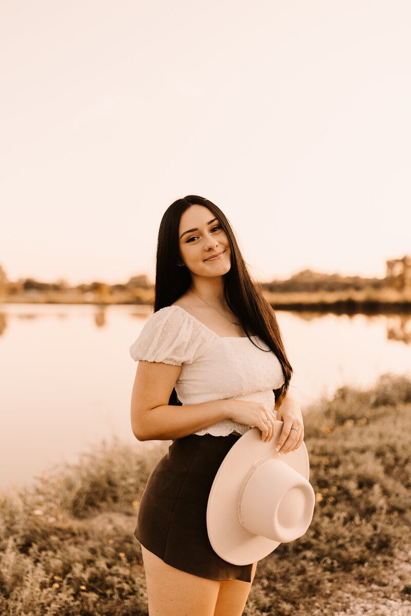 senior in front of a pond at sunset