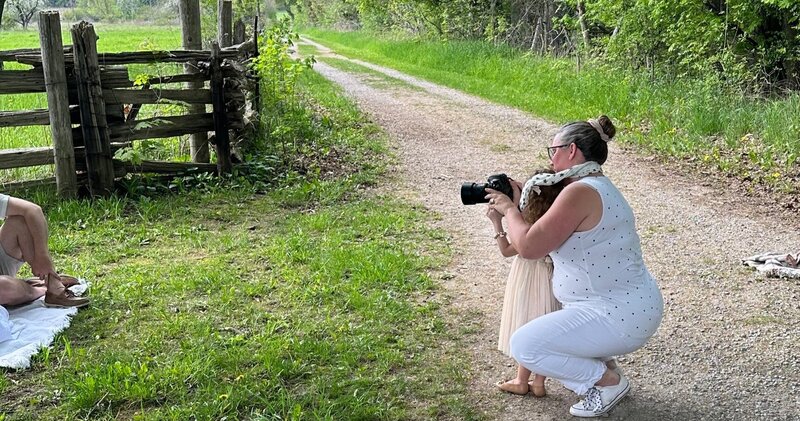 Denise and a child look through the camera together during a family photo session on a country path in Paris, Ontario.