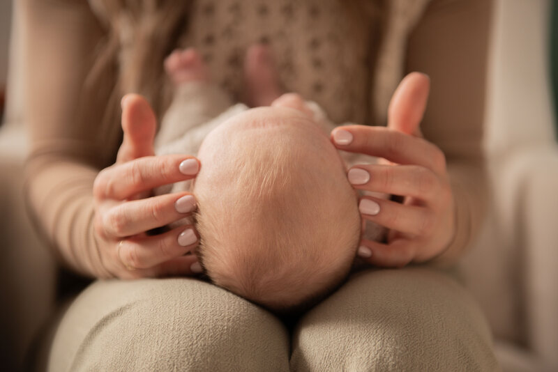 baby lying on a craniosacral therapist's lap with fingers placed to temples