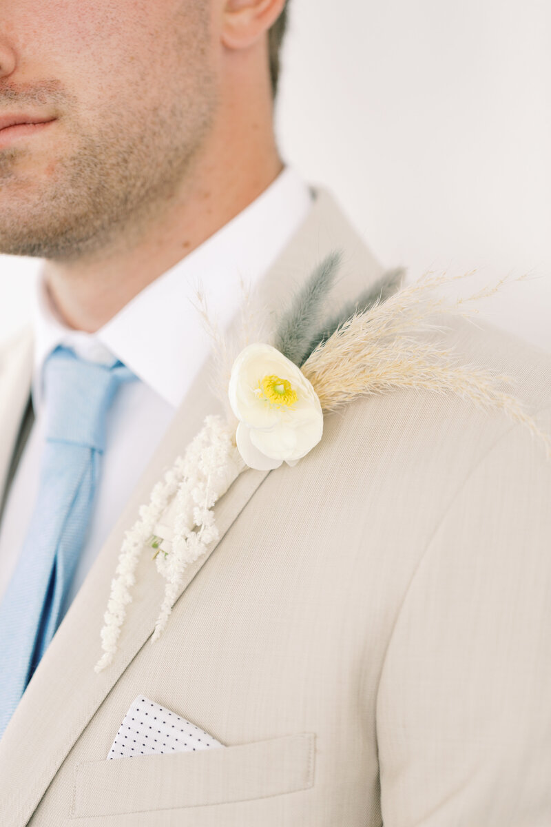 Soft florals and dried textures create a refined boutonnière for the modern groom.