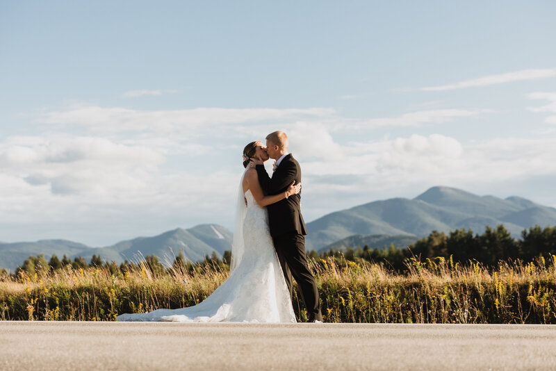 bride and groom kiss in front of mountain landscape