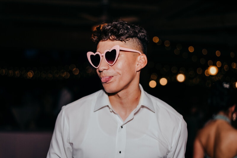 Groom wearing heart colored glasses at coastal discovery museum wedding