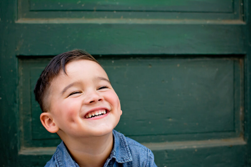 Little boy smiling in front of a green door