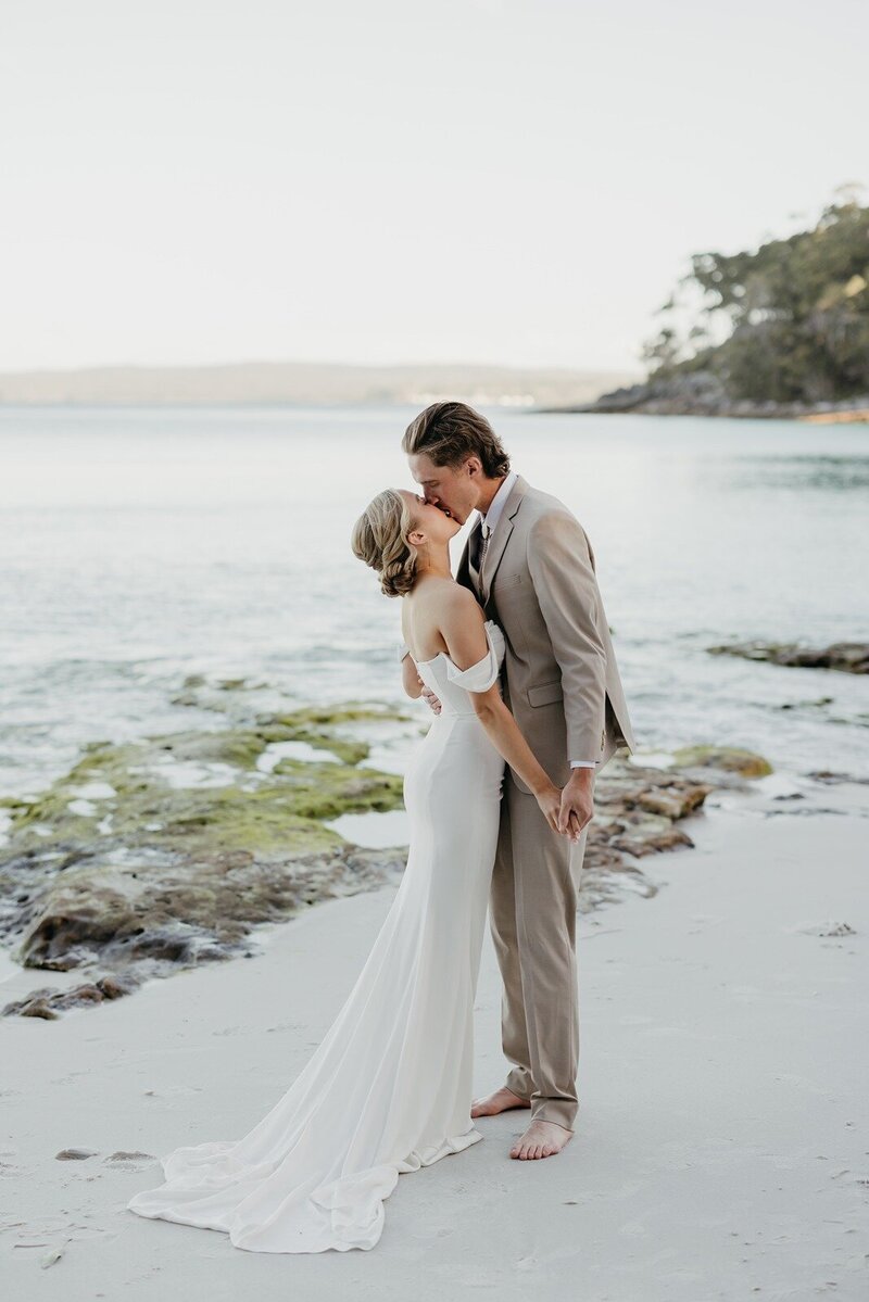 A bride and groom kissing on the beach at their elopement in Jervis Bay