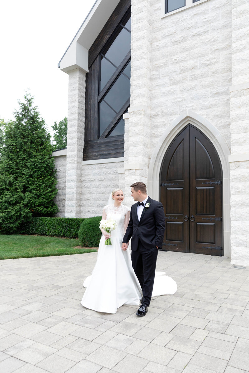 Black and white candid of joyful bride and groom walking outdoors after ceremony