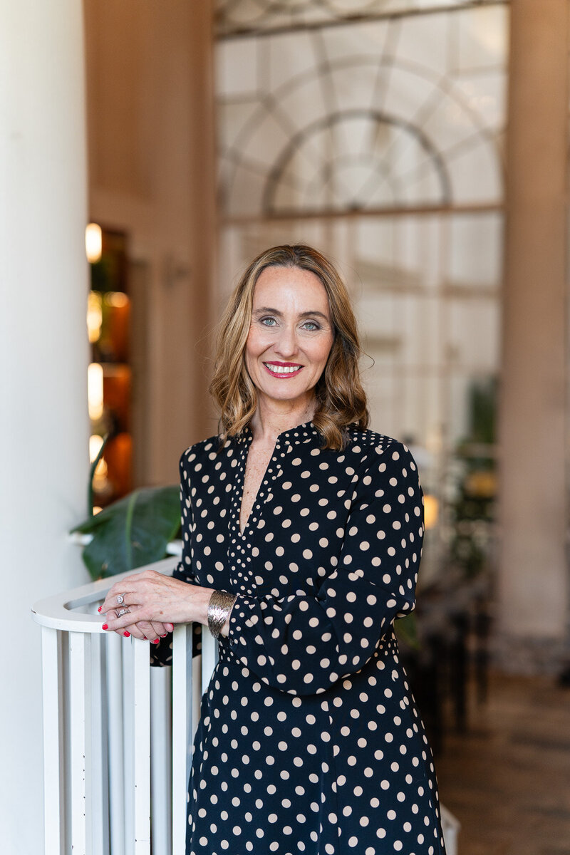 Standing woman leaning on railing and smiling confidently into the camera