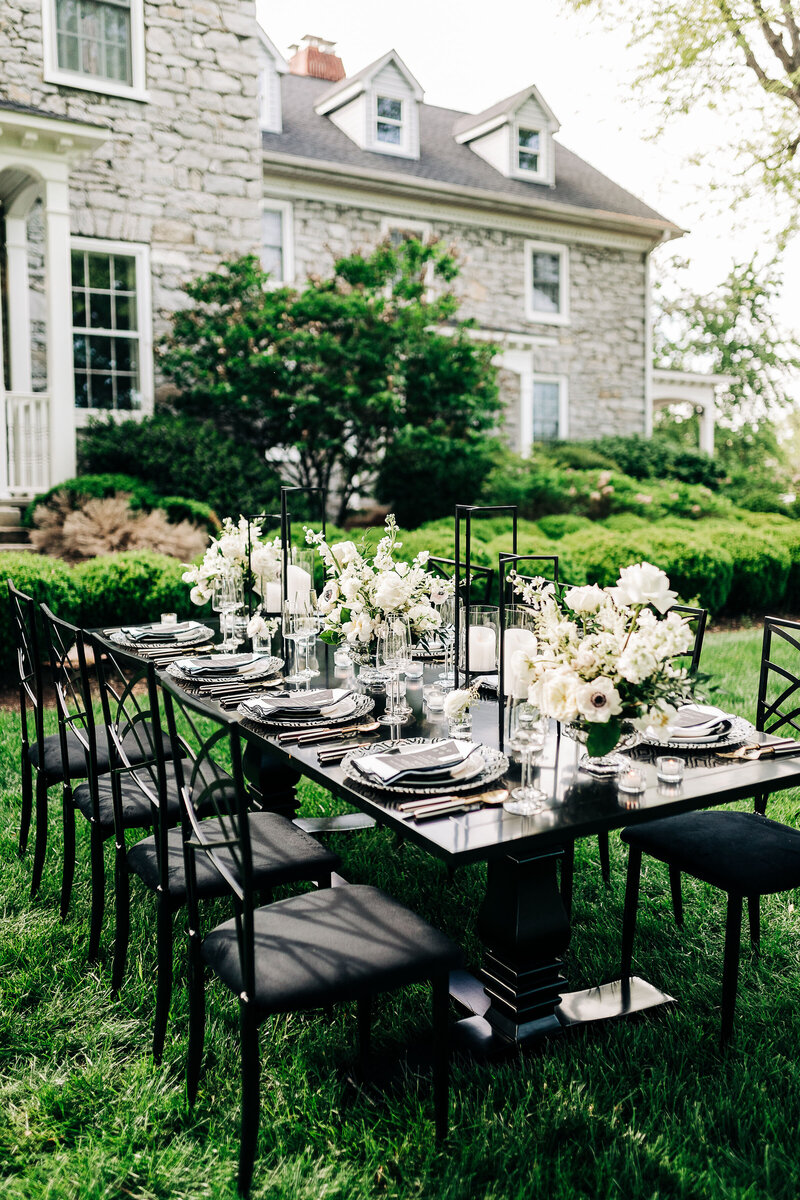 Marcia Alphonso weddings and events floral designer arranging a lush ceremony arch installation featuring greenery and pastel roses in a vibrant, elegant design.
