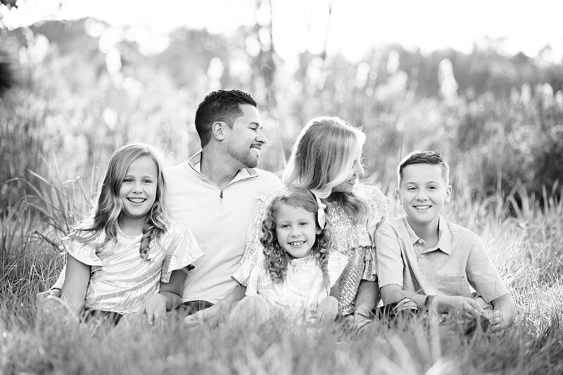 black and white photo of family of 5 sitting in a field by Orlando Family Photographer