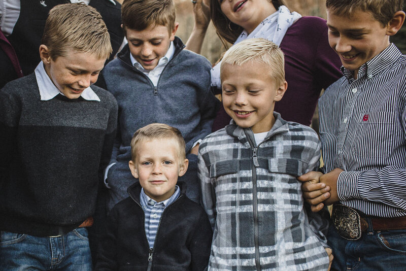 a bunch of boys smiling as they hug their biological and adopted brothers