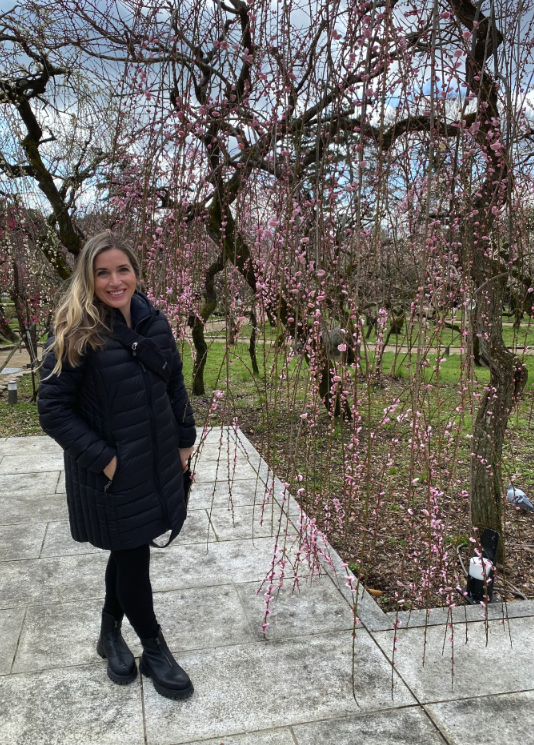 a woman stands in front of cherry blossoms in japan