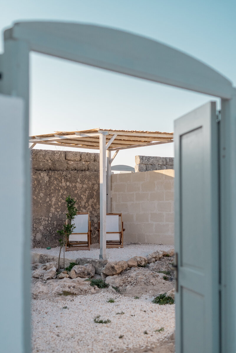 White Italian hotel with arched doorways and pots out front