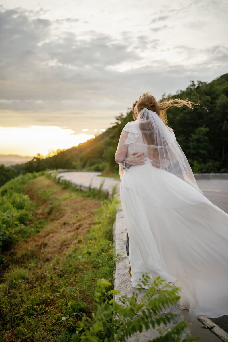 bride standing on a stone wall with her veil and gown blowing in the wind for a gatlinburg elopement