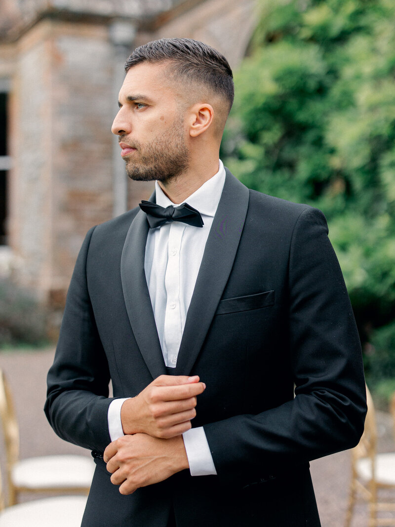 Portrait of groom adjusting his cufflinks and looking off to the side