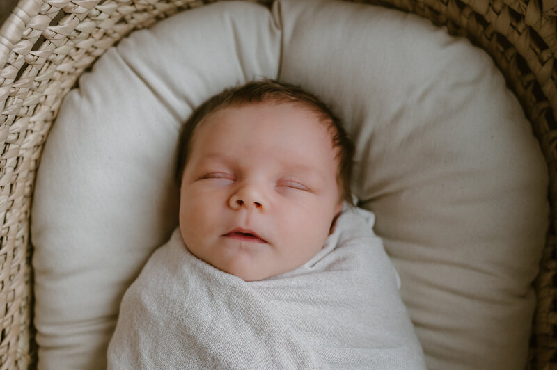 Newborn photoshoot includes a baby wrapped in a white blanket prop,  an intimate moment shot by Pittsburgh area photographer, Kristin Wieskamp