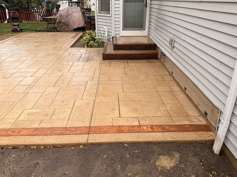 Ashlar-stamped concrete patio with a red border and steps in Middlebury, IN