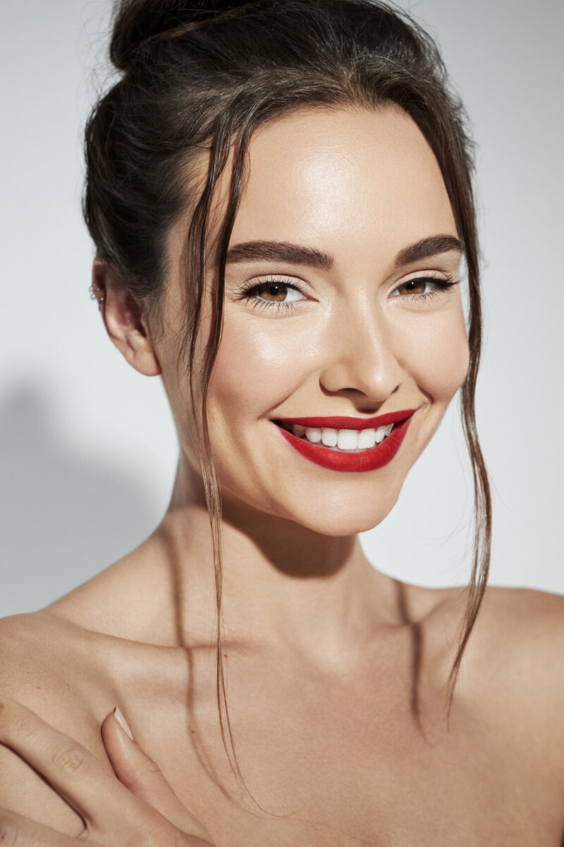 Luciana Cid in a vibrant beauty portrait, smiling brightly with red lipstick, captured by Ylva Erevall.