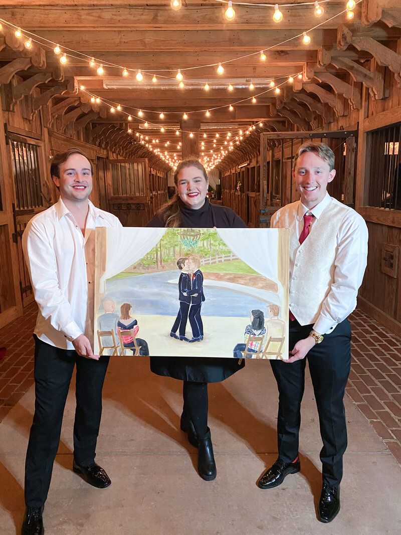 Elyse Stokes posing with a 24"x36" live wedding painting of two grooms sharing their first kiss on their wedding day
