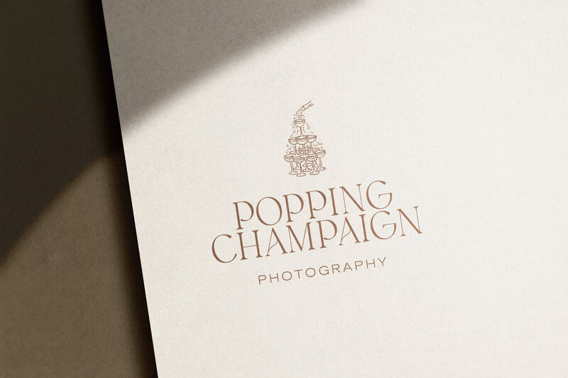 A business card with the logo and name "Popping Champaign Photography" featuring an illustration of stacked champagne glasses, perfect for those seeking wedding photography SEO or specialized SEO services for wedding photographers.