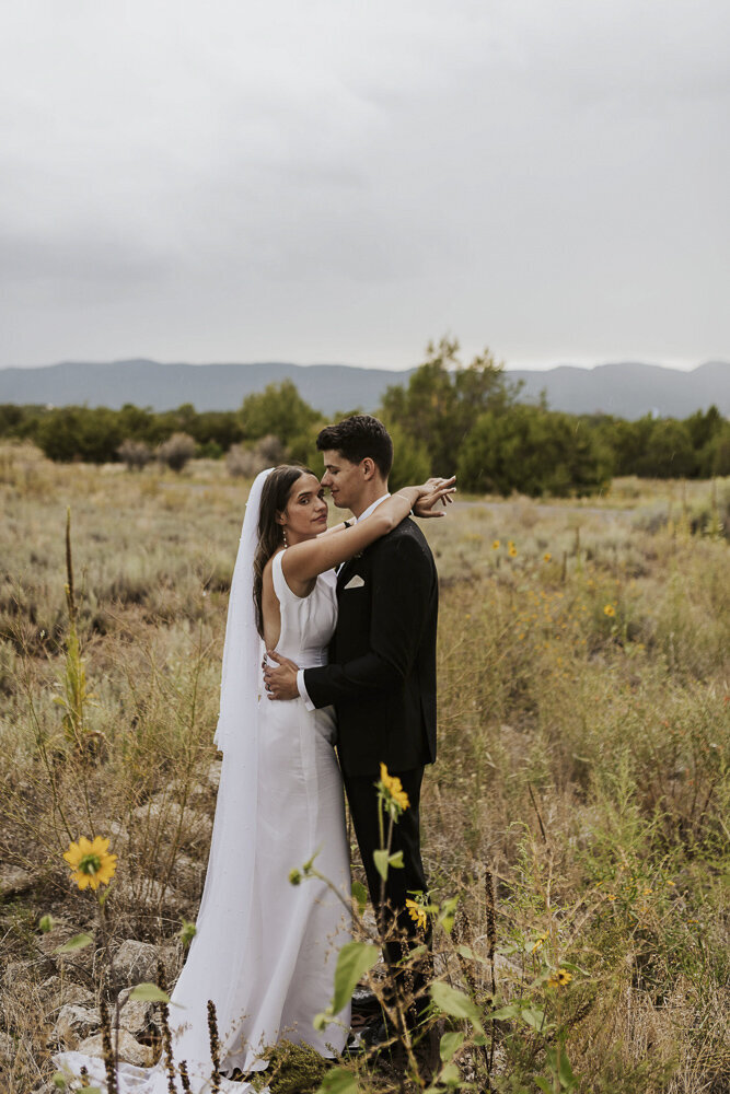 a bride and groom embracing in a field