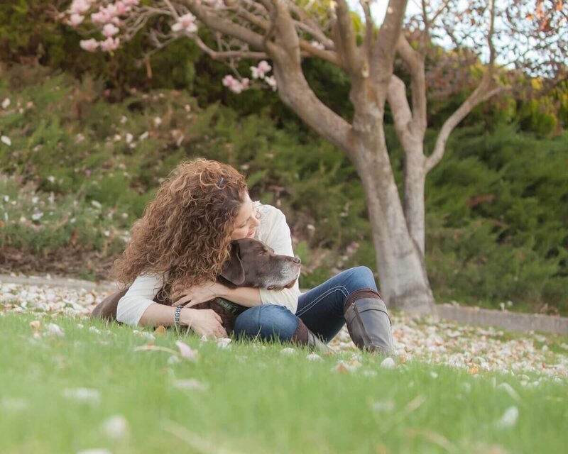 Photographer Lynette Smith cuddling her brown labrador outside in Wenatchee