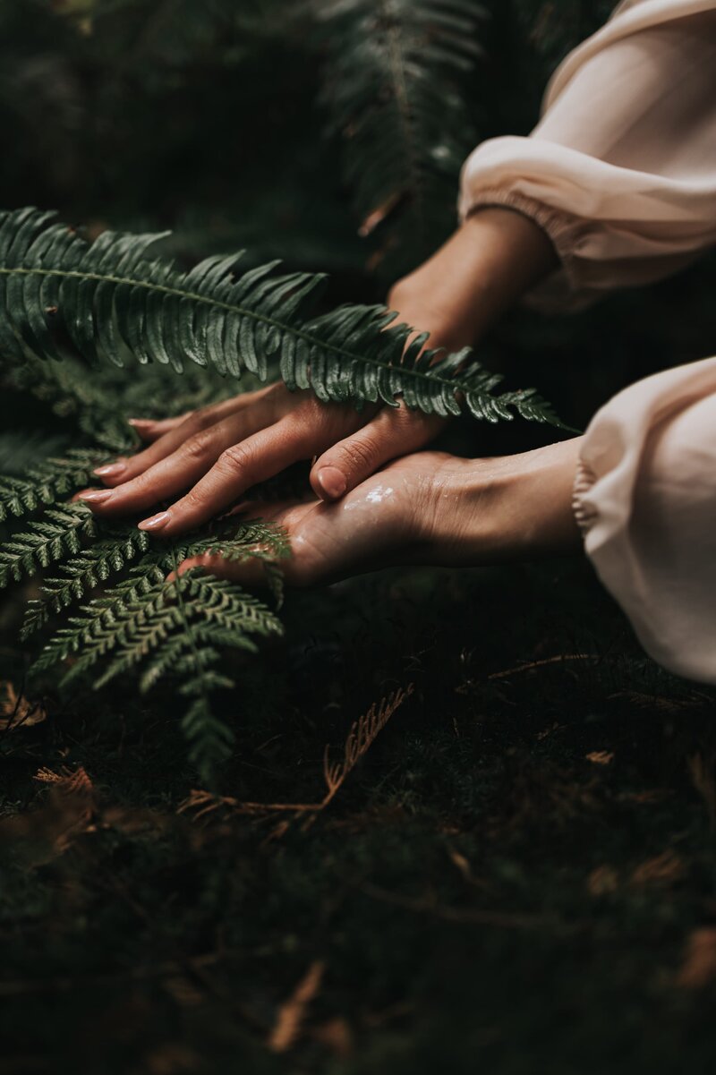 Women holds ferns in her hands in the forest.
