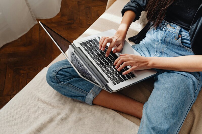 Woman wearing jeans sitting with a laptop on her legs