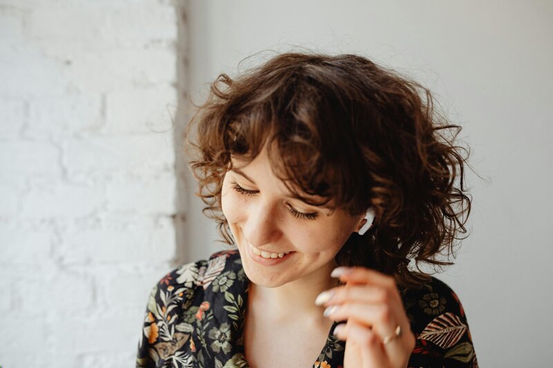 woman with headphones smiling and listening to a podcast